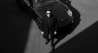 AI-edited photo of a person in a dark luxury porsche editorial scene with black dress shirt and black tie